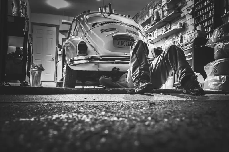 A mechanic working under a classic car