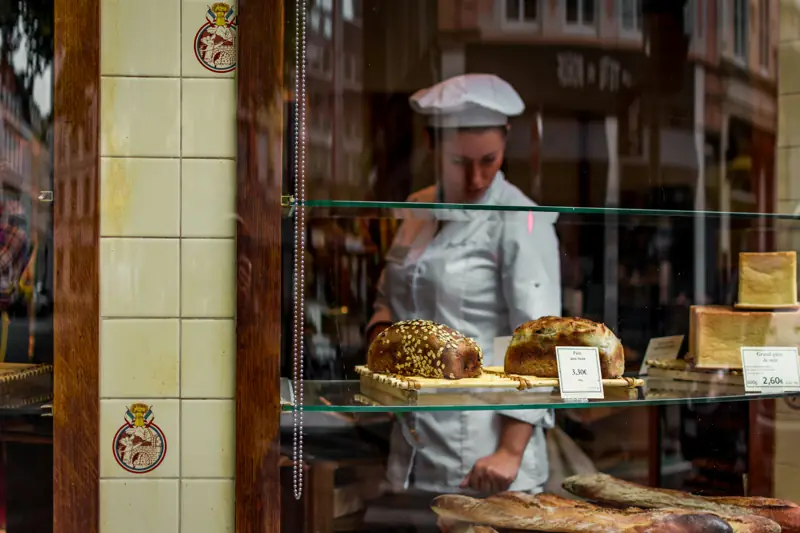 A baker arranging loaves behind a shop window