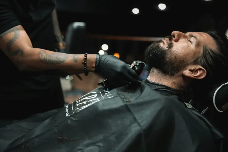 A barber trimming a client's beard
