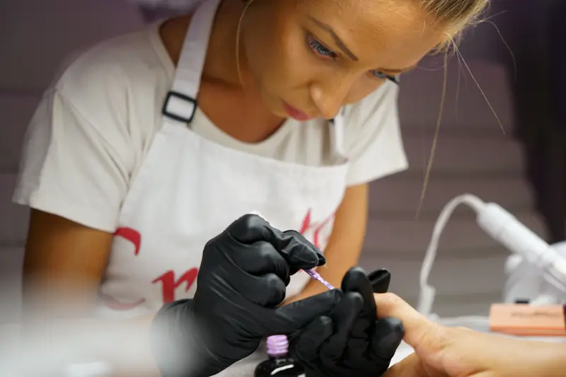 A nail technician painting a client's nails
