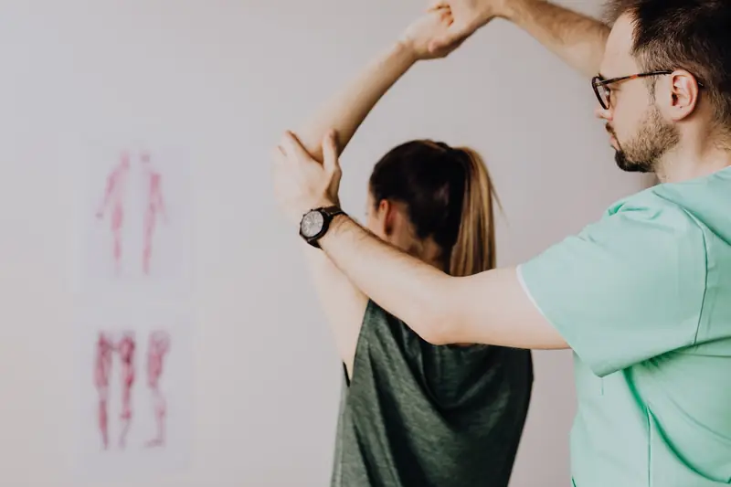 A physiotherapist stretching a patient's arm