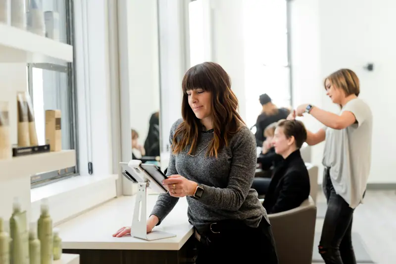 A salon owner looking at a tablet in her salon